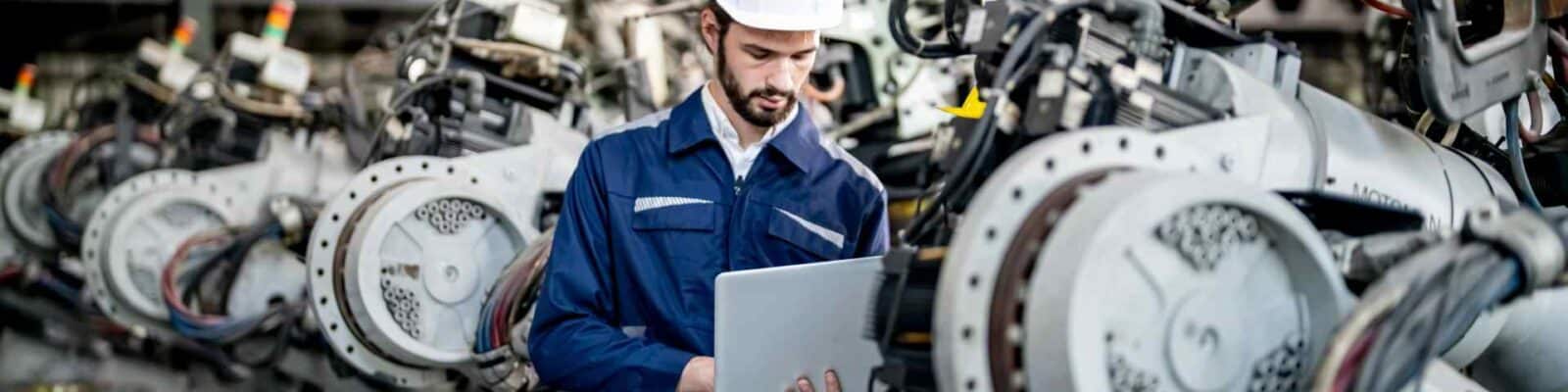 Engineer evaluating machinery with laptop.