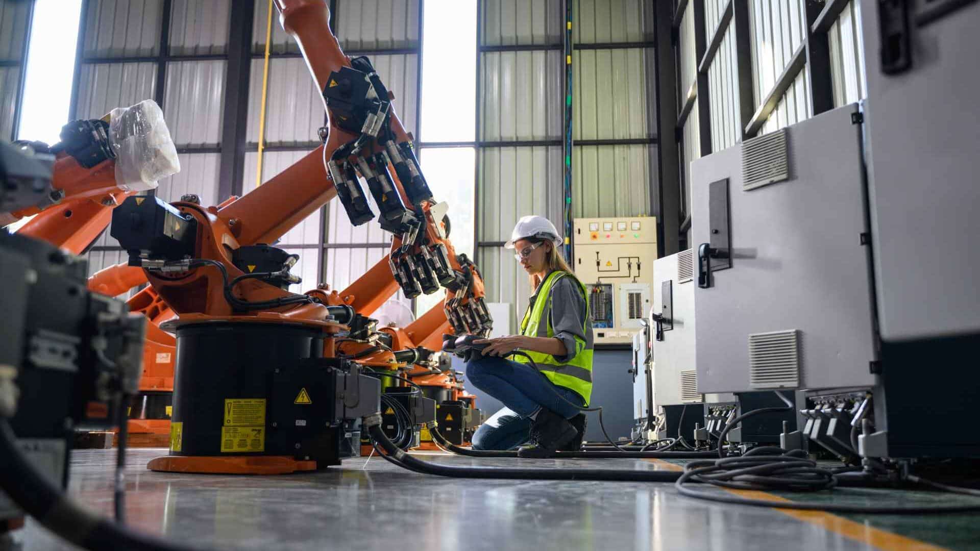 Technician servicing robotic equipment in factory.