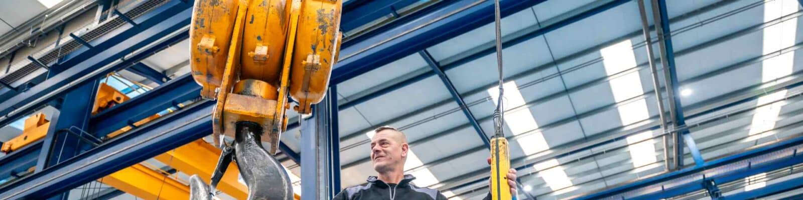 Worker operating a crane lifting device in warehouse