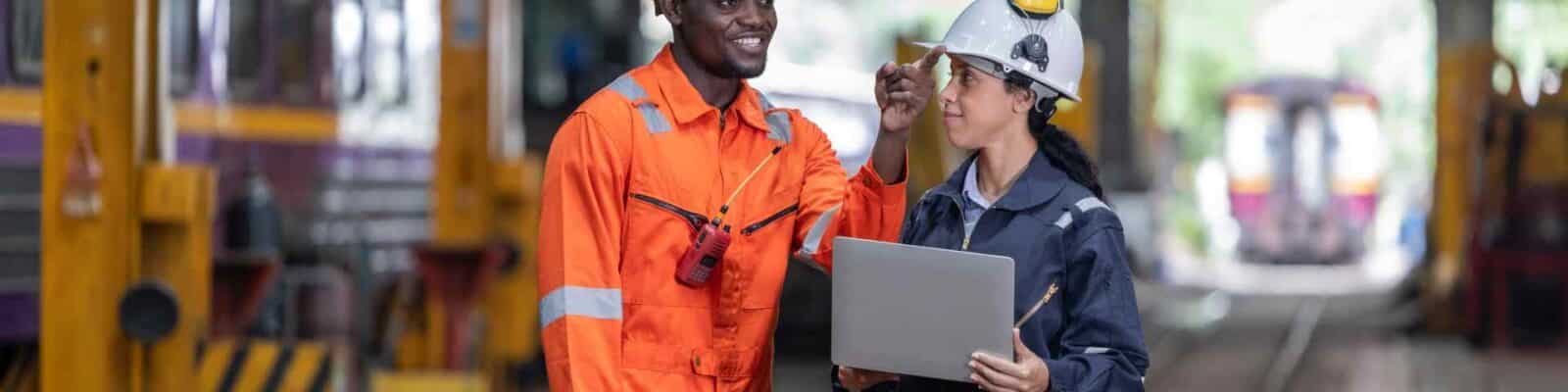 Workers discussing over laptop in industrial setting