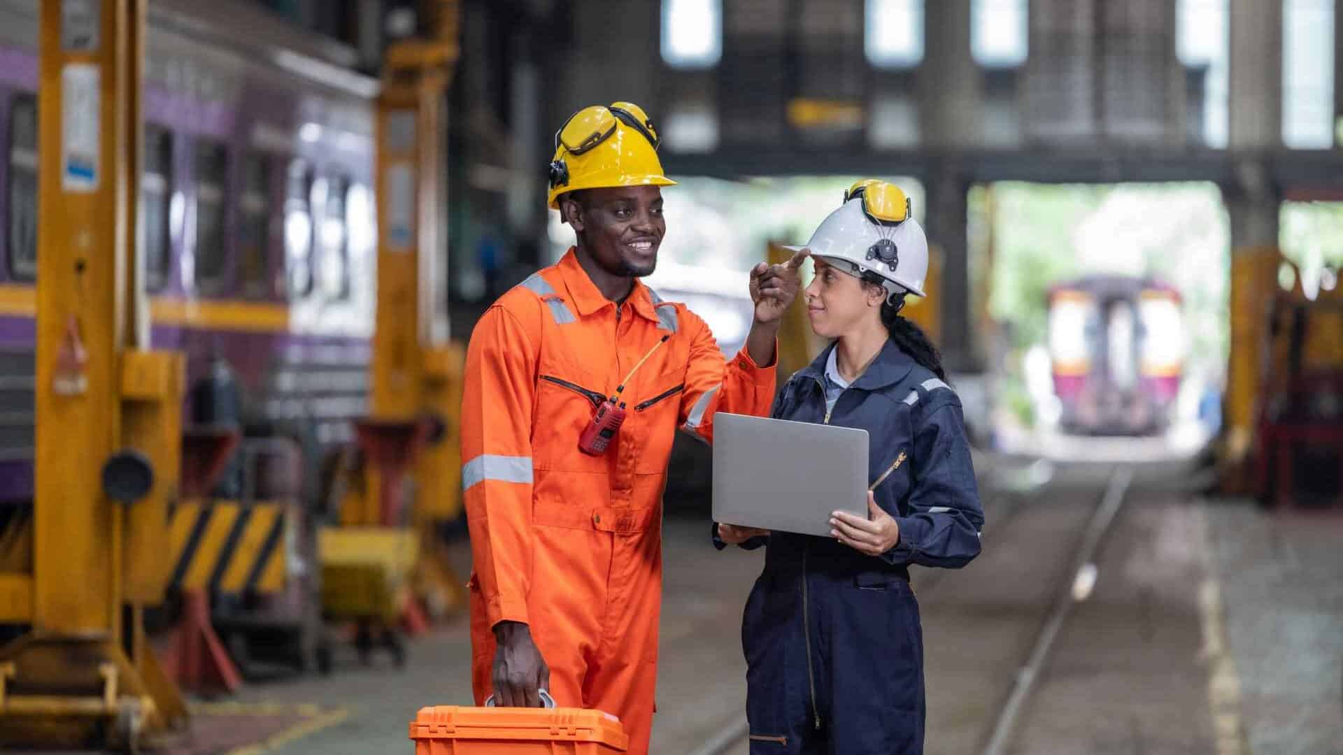 Workers discussing over laptop in industrial setting