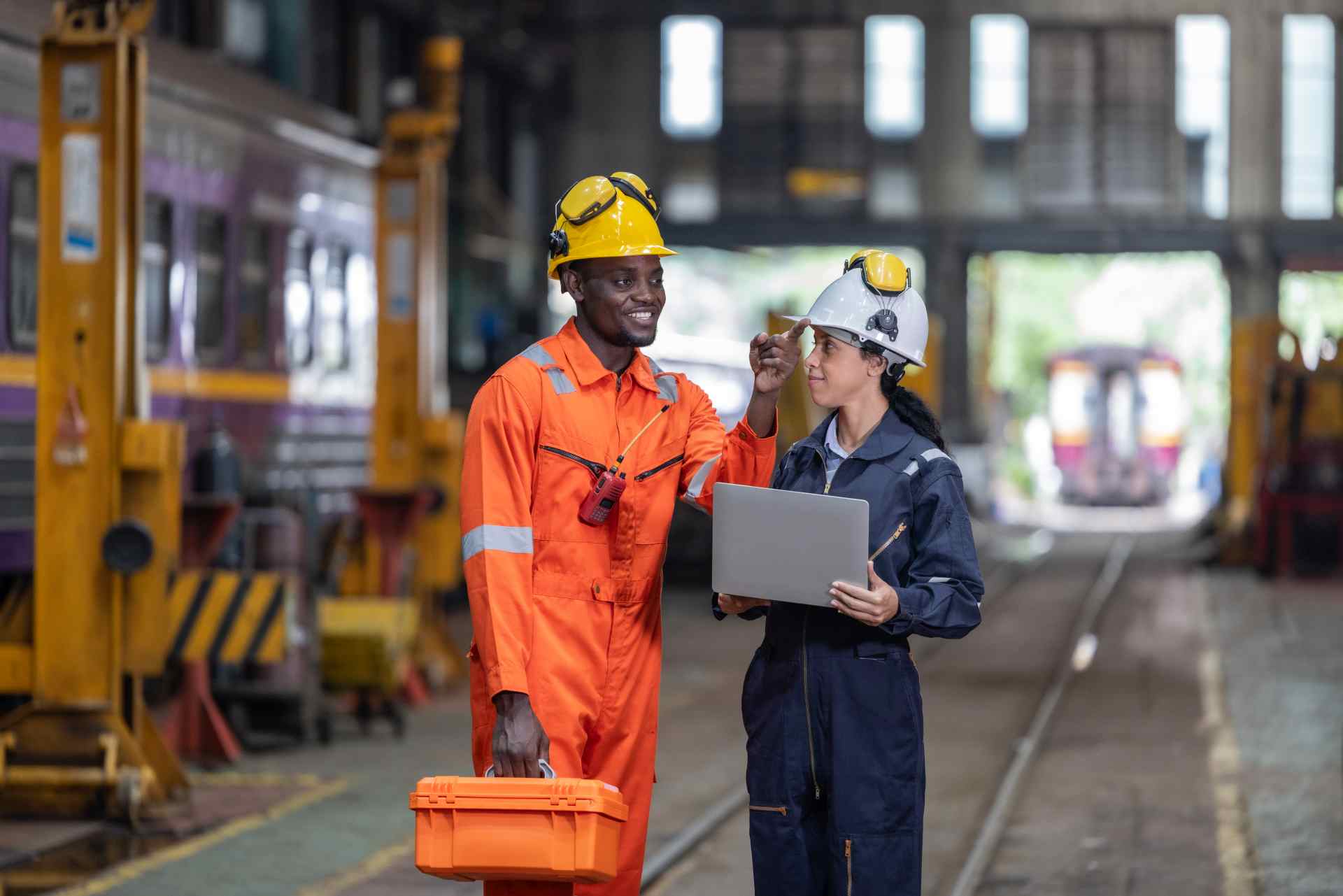 Workers discussing over laptop in industrial setting