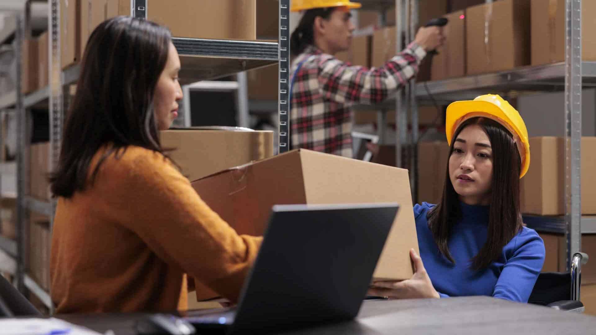 Warehouse workers managing inventory with laptop
