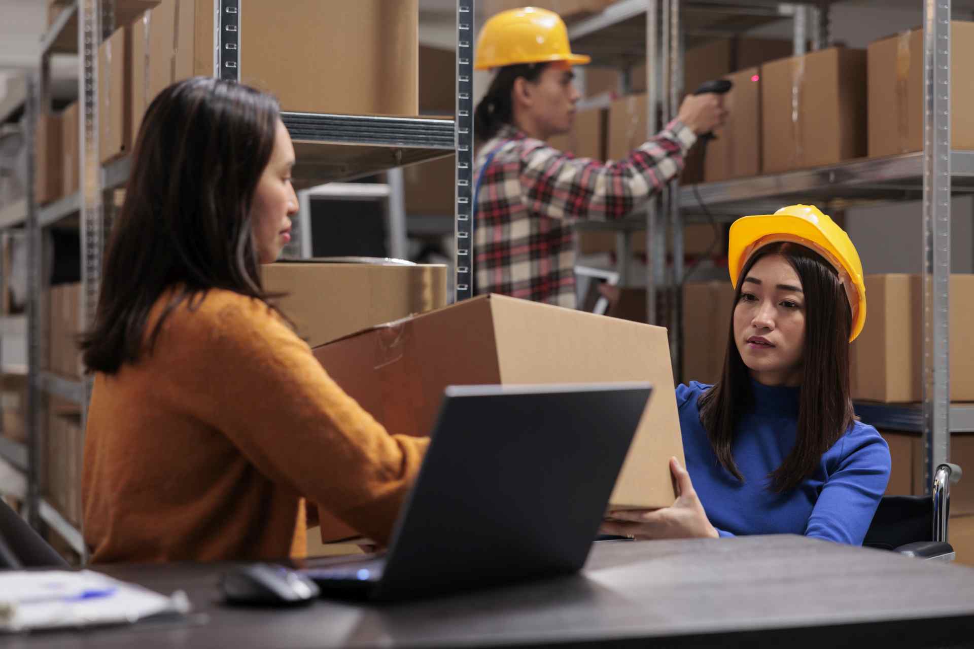 Warehouse workers managing inventory with laptop